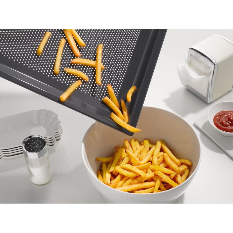 Frites sortant du four vers un bol blanc