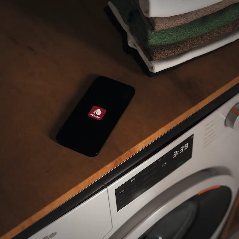 Smartphone sur machine à laver près de serviettes pliées