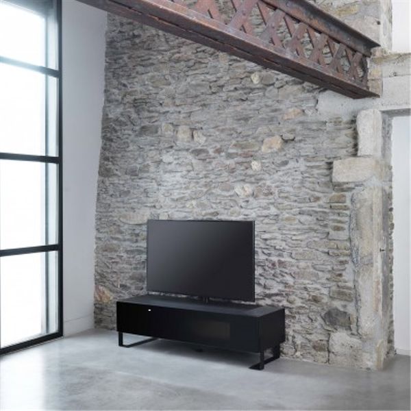 Télévision moderne sur meuble noir devant mur en pierre