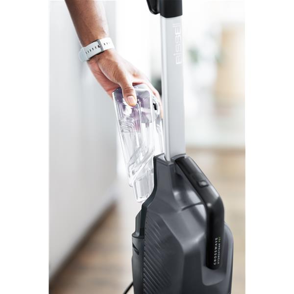 Personne retire le réservoir d’un aspirateur vertical.