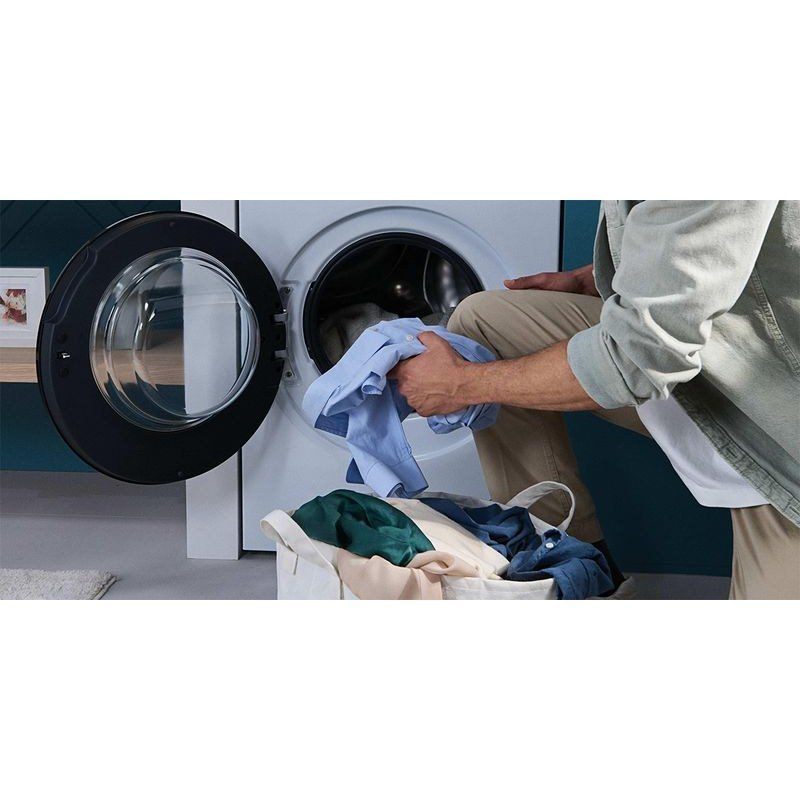 Homme charge du linge dans machine à laver