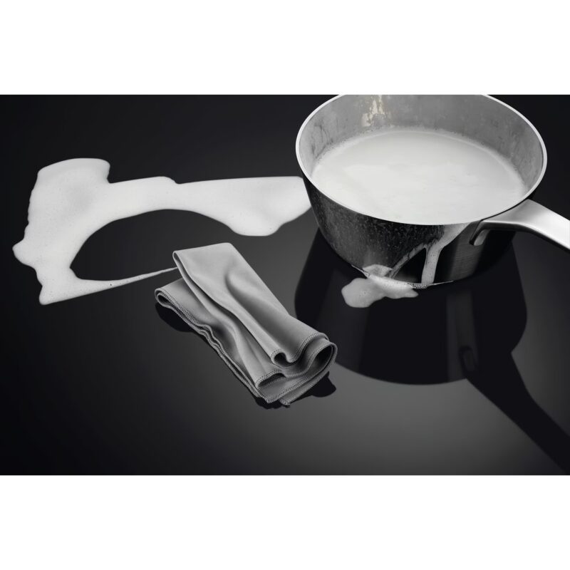 Lait débordant d’une casserole sur surface noire